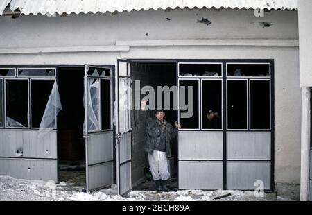 Januar 1994 während des Krieges in Zentralbosnien: Von einer Tür aus gibt ein Soldat der Rama Brigade der HVO das Siegeszeichen im bosnisch-muslimischen Dorf hier, das zwei Tage zuvor gefangen genommen wurde. Stockfoto