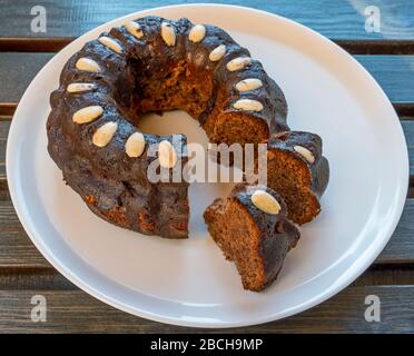 Der köstliche hausgemachte Kuchen namens Bundt, auf einer weißen Keramikplatte über einem Holztisch Stockfoto
