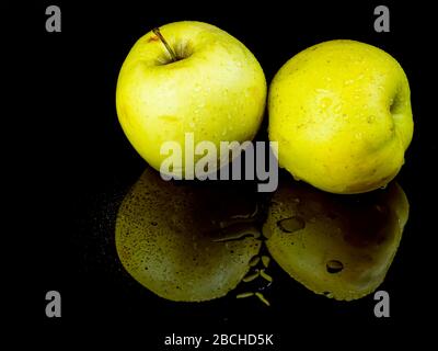 Obstgrüner apfel in Wassertropfen auf schwarzem Glashintergrund mit Spiegelung. Stockfoto