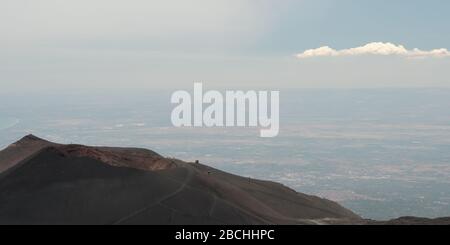 Panorama auf dem Ätna eines niedrigeren Vulkans und die fernen Länder mit einer langen einsamen Wolke, Sizilien, Italien. Stockfoto