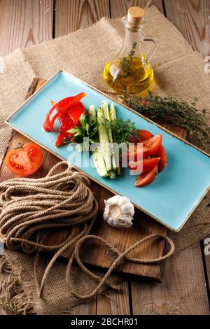 Geschnittenes frisches Gemüse auf blauen Platte auf hölzernen Tisch Hintergrund Stockfoto