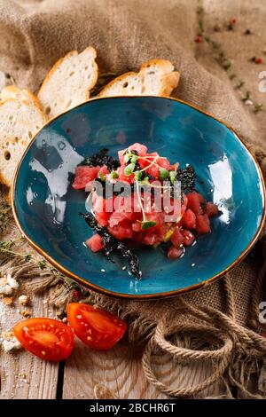Lachsartar, Tomaten, Rosmarin auf Holzbranntbrett Stockfoto