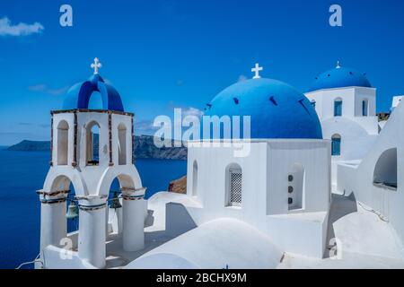 Santorini Griechenland, blaue Kuppelkirchen in Oia mit weißen Wänden gegen einen blauen Himmel. Oia berühmte drei blaue Kuppeln Stockfoto