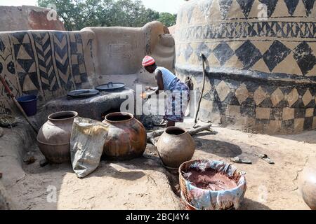 Afrika, Burkina Faso, Region Pô, Tiebele. Stadtansicht des königlichen Hofdorfes in Tiebele. Eine Frau kocht Stockfoto