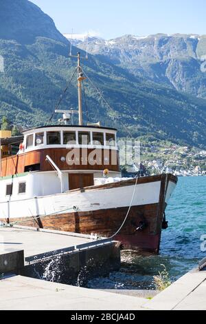 ODDA, NORWAY-CIRCA JUL, 2018: Kleines Kreuzfahrtschiff zu mieten ist im Hafen im Zentrum der Stadt Odda vermoorten. Die Lindesnes Hytteutonie verfügt über Motorboote Stockfoto