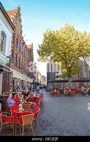 Venlo, Limburg-Niederlande - 13. Oktober 2018: Straße mit Cafés, Restaurants und Bars im historischen Zentrum der niederländischen Stadt. Leute, die in den Gärten sitzen. Vertikales Foto. Stockfoto