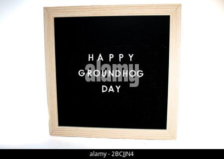 Ein schwarzes Schild mit weißen Buchstaben, die Happy Groundhog Day auf einem weißen Hintergrund sagt Stockfoto