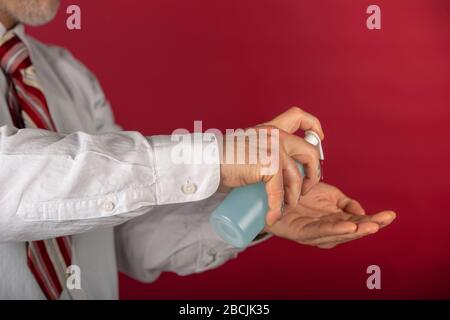 Der Mensch verwendet einen Desinfektionsmittel-Gelspender zum Händewaschen, gegen neue Coronavirus- oder Corona-Viruserkrankung auf rotem Grund. Stockfoto