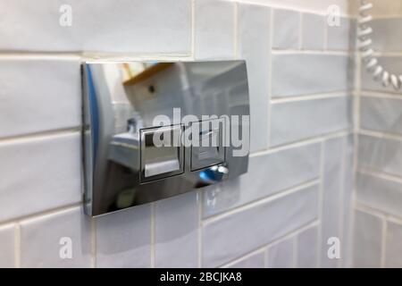 Modernes Bad aus Edelstahl, Metalllichtschalter mit Spiegelung an Fliesen, gefliester Wand aus Raum und Knopf Stockfoto