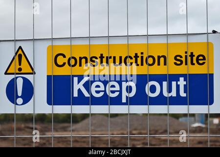Baustelle halten Sie Schild auf Metallzaun mit verschwommenen Bauarbeiten im Hintergrund Stockfoto