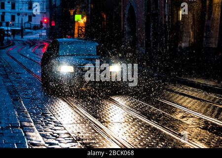 Lwiw, Ukraine Altstadt in Lvov nachts mit Schneewetterstraße und Auto in Gasse mit Reflexion von Scheinwerfern und Schneeflocken im Winter Stockfoto