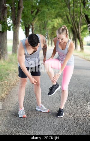 Der Mann unterstützt eine Frau, die sich beim Sport verletzt hat Stockfoto