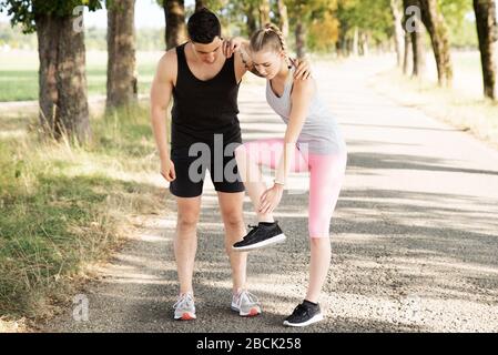 Der Mann unterstützt eine Frau, die sich beim Sport verletzt hat Stockfoto