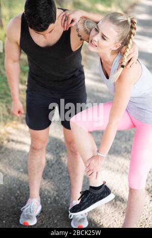 Der Mann unterstützt eine Frau, die sich beim Sport verletzt hat Stockfoto