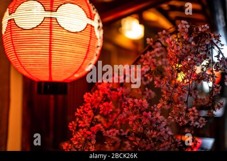 Kyoto, Japan Gasse bunte Straße im Gion Viertel nachts mit Nahaufnahme von beleuchteter roter Papierlaterne Lampe und Kirschblütenblumen deco Stockfoto