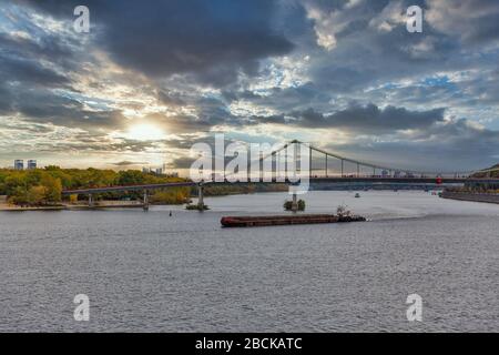 Stadtbild mit Fußgängerbrücke über den Fluss Dnjeper bei Sonnenuntergang in Kiew, Ukraine. Stockfoto