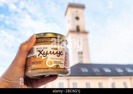 Lwiw, Ukraine - 21. Januar 2020: Ukrainische Lvov Altstadt rynok Platz rada Rathaus und Nahaufnahme des lokalen veganen Lebensmittelunternehmens Produkt namens Hummus mA Stockfoto