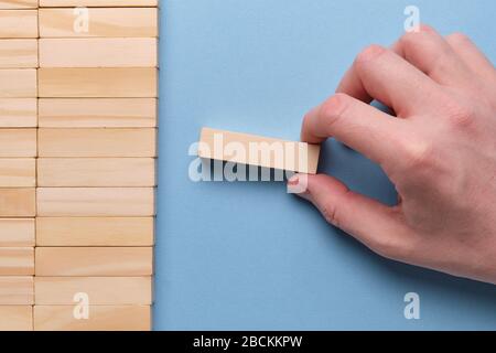 Hand hält Holzklotz auf blauem Grund. Nahaufnahme. Stockfoto