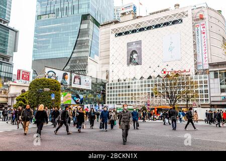 Tokio, Japan - 28. März 2019: Berühmte Shibuya Kreuzung in der Innenstadt mit einer Gruppe von vielen Menschen, die tagsüber Masken tragen Stockfoto