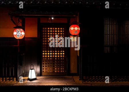 Kyoto, Japan - 9. April 2019: Hintergasse im Gion Viertel nachts mit Schildern und beleuchteten roten hängenden Papierlaternen am Eingang zum gehobenen Hotel Stockfoto