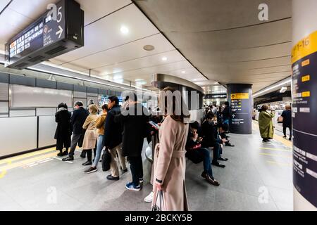 Shibuya, Japan - 1. April 2019: Menschen, die während der Hauptverkehrszeit in der U-Bahn im Inneren von Stati in einer Linie auf U-Bahn-Wagen auf dem Bahnsteig warten Stockfoto