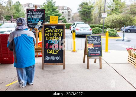 Reston, USA - 1. April 2020: Händler Joes Lebensmittelladen unterzeichnen für ältere behinderte Kunden spezielle Stunden, Kundenlimit und Lebensmittelverpackungen Papiertüte Stockfoto