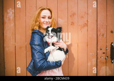 Nationaler Haustiertag. Eine junge Frau hält einen Hund in den Händen. Einen Hund kaufen. Glück. Tiere lieben. Tierarzneimittel für Haustiere. Tierklinik Stockfoto