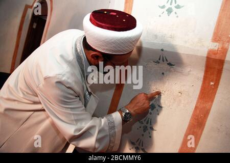 ISTANBUL, TÜRKEI - 23. JULI: Prayer Leader (Imam) zeigt alte arabische Graffiti in der Arap Moschee am 23. Juli 2013 in Istanbul, Türkei. Die Moschee war ursprünglich eine im Jahre 1325 errichtete Römisch-Katholische Kirche. Stockfoto