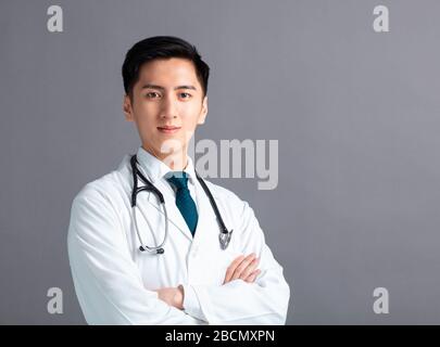 Portrait des männlichen asiatischen jungen Arztes auf grauem Hintergrund Stockfoto