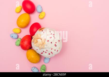 Osterkuchen auf pinkfarbenem Hintergrund neben gefärbten Wachtelpastell- und Hühnereiern. Ostergeschenkkarte. Stockfoto