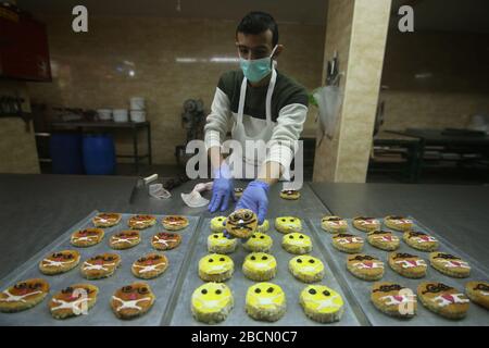 Rafah, Palästina. April 2020. Der palästinensische Bäcker Salim Abu Ayadah, der in einer Bäckerei mit Gesichtsmasken die Situation von Covid-19 zum Thema Backwaren machte, schafft Bewusstsein gegen die Ausbreitung von Coronavirus in Rafah, im südlichen Gazastreifen, Palästina, 4. April 2020. Kredit: SIPA USA/Alamy Live News Stockfoto