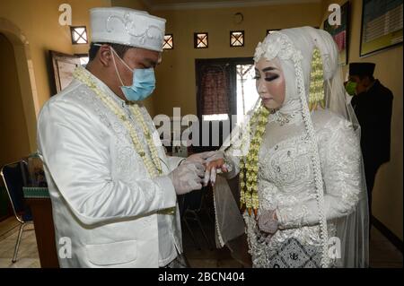 Süd-Tangerang, Indonesien. April 2020. Ein Bräutigam legt bei einer Hochzeitsfeier während des COVID-19-Ausbruchs in South Tangerang, Indonesien, am 4. April 2020 einen Ring auf den Finger der Frau. Die indonesische Regierung sagte am Samstag, dass die Anzahl der bestätigten Fälle von COVID-19 im Land auf 2.092 angestiegen sei, wobei die Zahl der Todesopfer auf 191 kletterte. Credit: Agung Kuncahya B./Xinhua/Alamy Live News Stockfoto