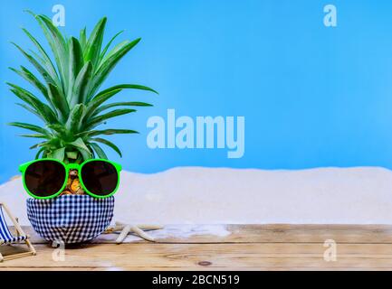 Ananas mit Sonnenbrille auf Holzhintergrund. Kreatives minimales Sommerferienkonzept Stockfoto