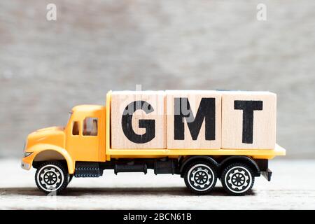 LKW hält Buchstabenblock in Wort GMT (Abkürzung von Greenwich Mean Time) auf Holzhintergrund Stockfoto