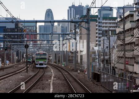 Ein Zug der Serie E231-500 auf der JR Yamanote-Linie vor der Shinjuku-Skyline mit dem Cocoon Tower im Zentrum von Tokio, Japan. Stockfoto