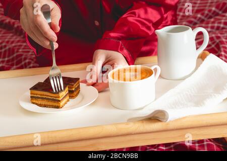 Tasse Kaffee mit Milch und Schokoladenkuchen. Süßes köstliches Frühstück auf einem Tisch mit Betttablett Stockfoto