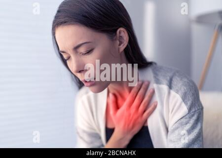 COVID-19 Kurzatmigkeit Coronavirus Hustenatmungsproblem. Asian Woman berührt Brust bei Schmerzen mit rot hervorgehobener Stelle. Atemsymptome Fieber, Husten, Körperschmerzen. Stockfoto