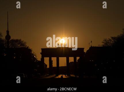 Berlin, Deutschland. April 2020. Hinter dem Brandenburger Tor erhebt sich die Sonne. Kredit: Paul Zinken / dpa-zb-Zentralbild / dpa / Alamy Live News Stockfoto