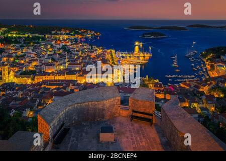 Tolle Aussicht auf die Adria und die Inseln von der Festung Tvrdava Fortica ( Spanjola) am Abend. Majestätische Hvar Stadtlichter und Hafen mit Luxus ya Stockfoto