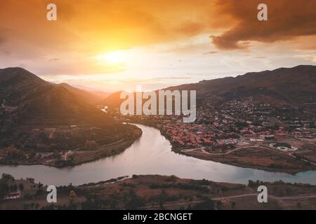 Goldener Sonnenuntergang über dem Tal mit Flüssen und Bergen. Panoramablick auf die Stadt Mtskheta und Kura mit den Flüssen Aragvi vom Kloster Jvari. Geo Stockfoto