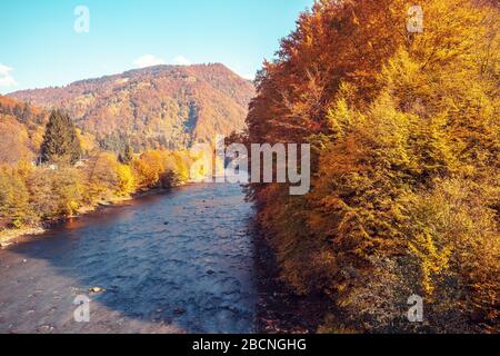 Schöne Naturlandschaft. Gebirgsfluss mit felsigen Hügeln bei Sonnenuntergang im Herbst Stockfoto