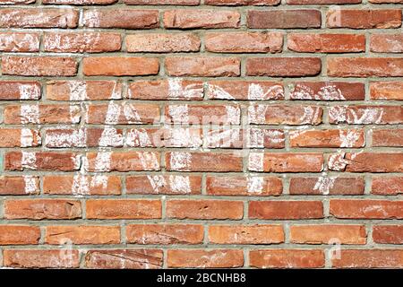 Rote Ziegelwand mit dem Wort glücklich in weißer Kreide von Hand gezeichnet. Positiver Graffiti-Hintergrund. Stockfoto