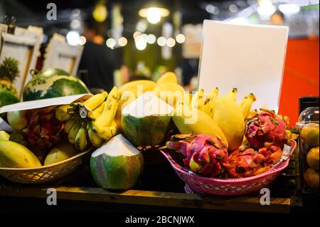 Tropische thailändische Früchte stehen auf dem lokalen Lebensmittelmarkt in Thailand. Kokosnuss, Libelle, Banane und Mango am Abend fair. Stockfoto