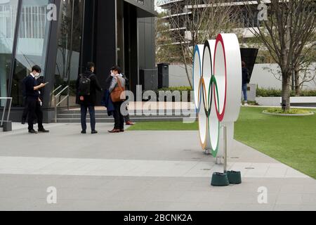 Menschen außerhalb des Japan Olympic Museum neben einem olympischen Ringe Denkmal. Sie tragen während des Coronavirus-Ausbruchs Gesichtsmasken. Stockfoto