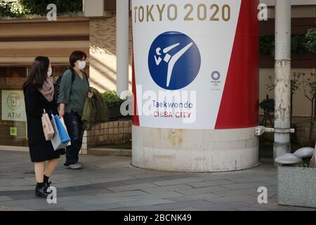 Menschen passieren eine eingewickelte Säule in Chiba City, die für die Olympischen Spiele in Tokio wirbt. Sie tragen Gesichtsmasken während des Coronavirus-Ausbruchs. Stockfoto