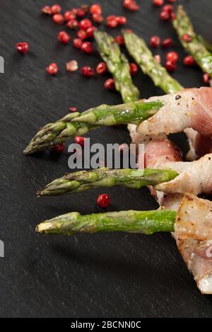 Spargel mit Speck serviert auf schwarzem Stein. Gesunde Lebensmittel - Frühstück. Dunkle Lebensmittel Hintergrund Stockfoto