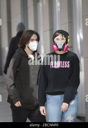 Vancouver, Kanada. April 2020. Ein Bürger, der eine Gesichtsmaske trägt, und ein anderer, der eine Atemschutzmaske trägt, gehen auf der Straße in der Innenstadt von Vancouver, Kanada, am 4. April 2020. Kredit: Liang Sen/Xinhua/Alamy Live News Stockfoto