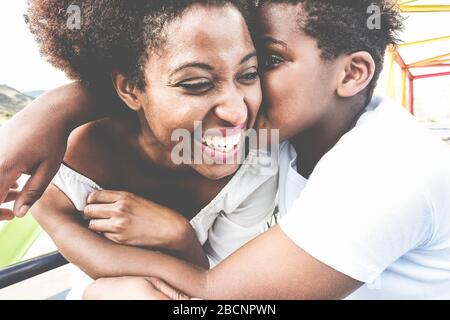 Fröhliche junge Mutter, die im Sommertag mit ihrem Kind Spaß hat - Son küsst seine Mutter im Freien - Familienleben, Mutterschaft, Liebe und zärtliche Momente konce Stockfoto