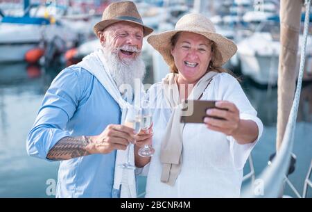 Fröhliches älteres Paar macht selfie, jubelt mit Champagner auf einem segelboot während des Jubiläumsurlaubs - Fröhlicher älterer Lebensstil, Liebe, Reisen und Holid Stockfoto