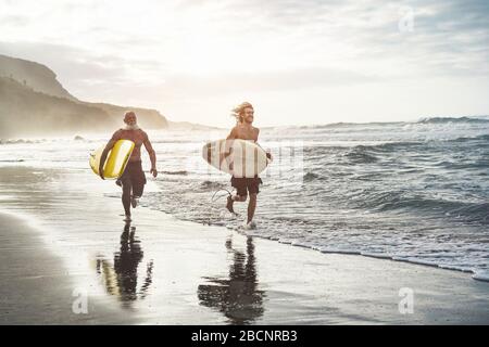 Mehrgenerationige Freunde, die am tropischen Strand surfen - Familienmitglieder haben Spaß am Extremsport - fröhliches älteres und gesundes Lifestyle-Konzept Stockfoto